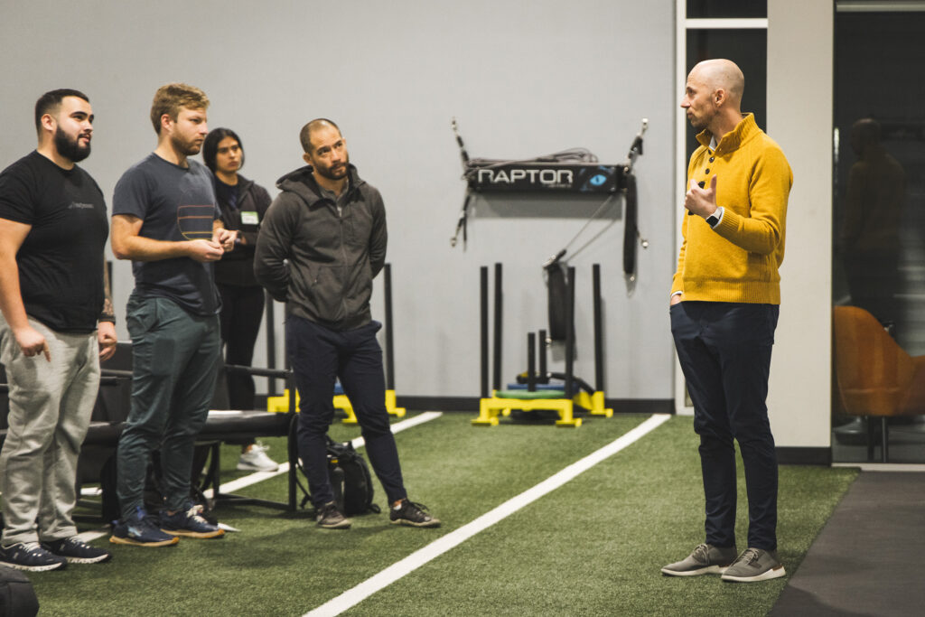 Zac Cupples teaching on a turf green in a gym