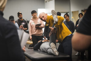 Zac Cupples testing hip flexion range of motion in front of a seminar crowd