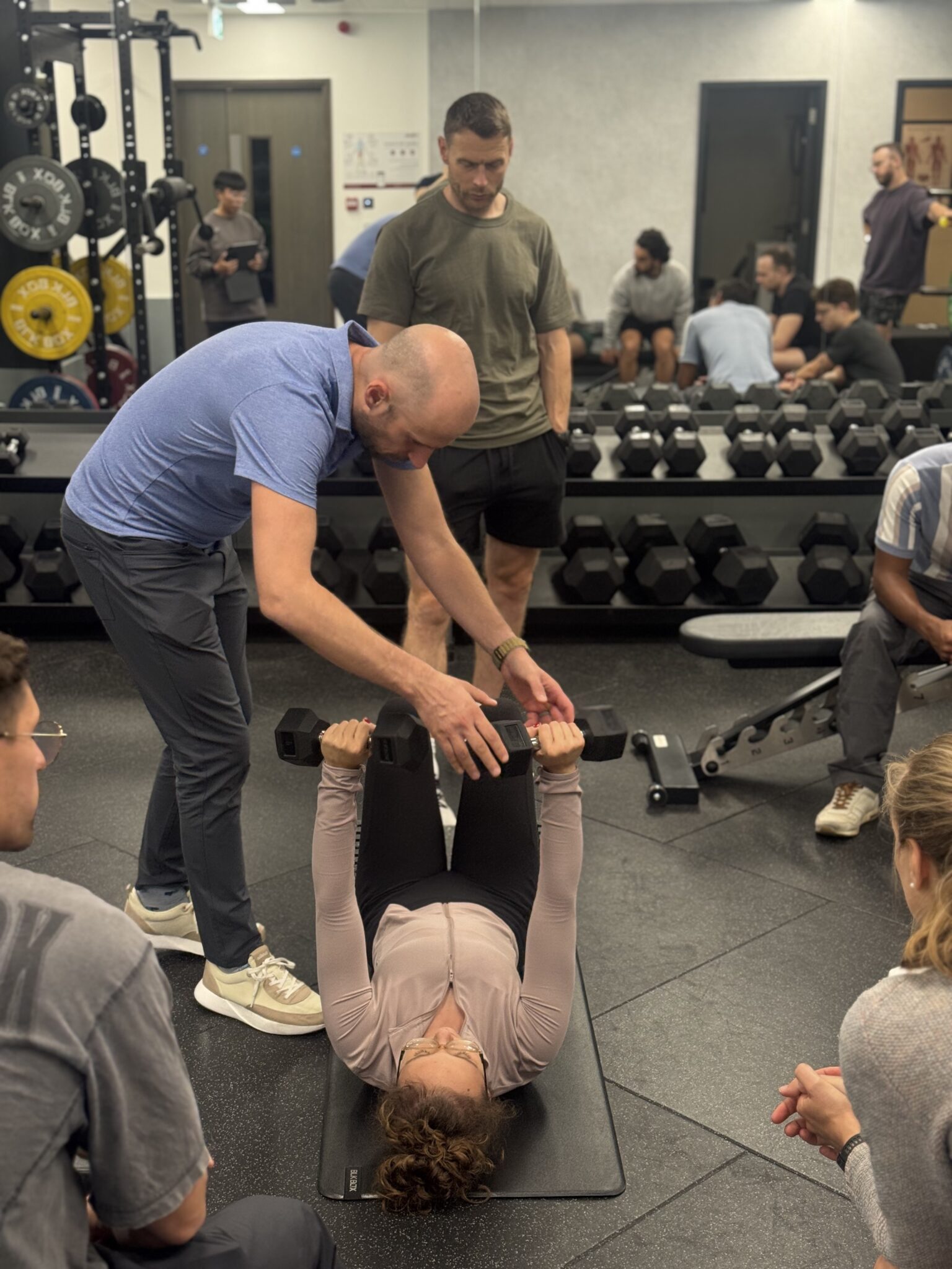 Zac Cupples coaching a woman laying on the ground during a class